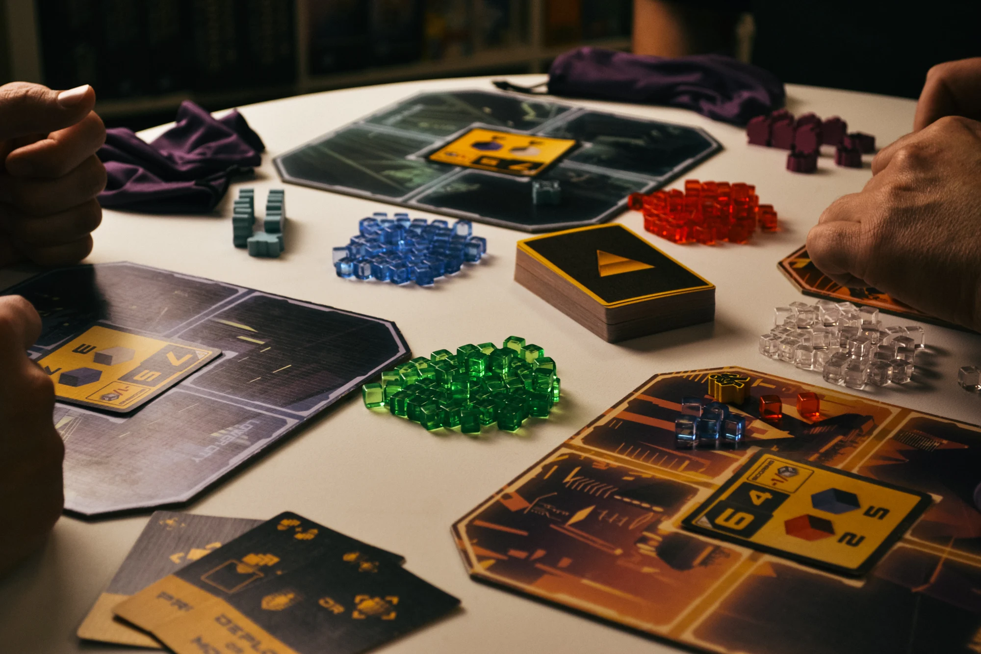 Players around a table with Hyperwars district boards, agents, and goods